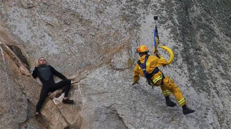 man clinging to a cliff rescued